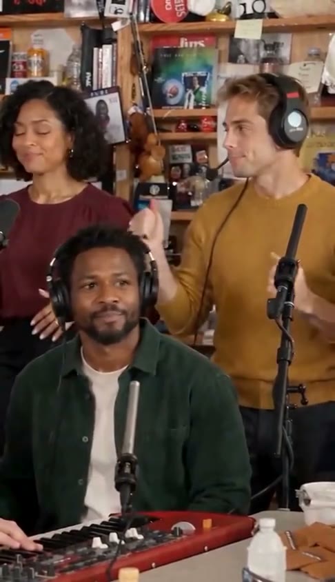 Demo frame showing the keyboardist and backing singers among wooden shelves
